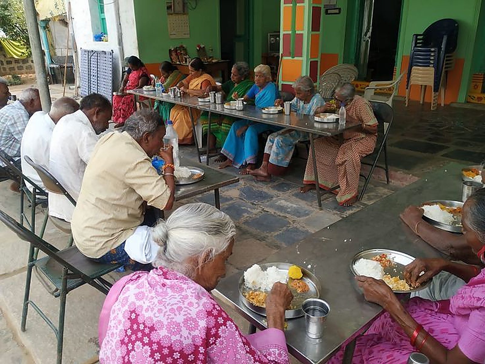 Elders share a midday meal together at long tables in the courtyard of the Karuna Day Care Centre.